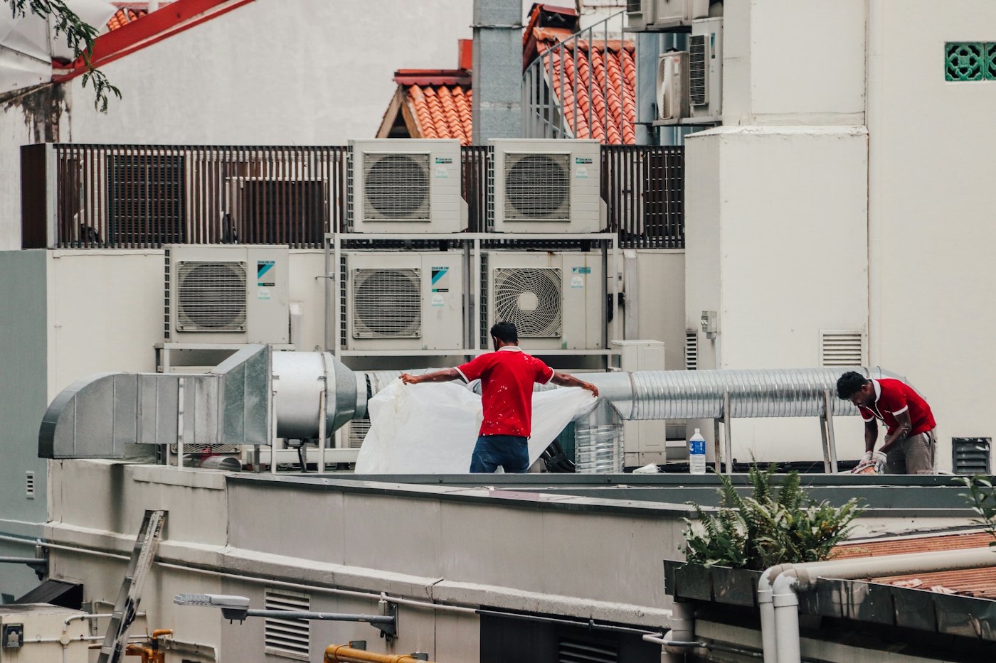 Technicians working beside rooftop air conditioning units